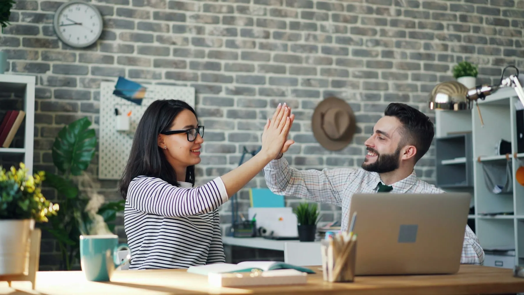 Collega’s kijken glimlachend naar een laptop