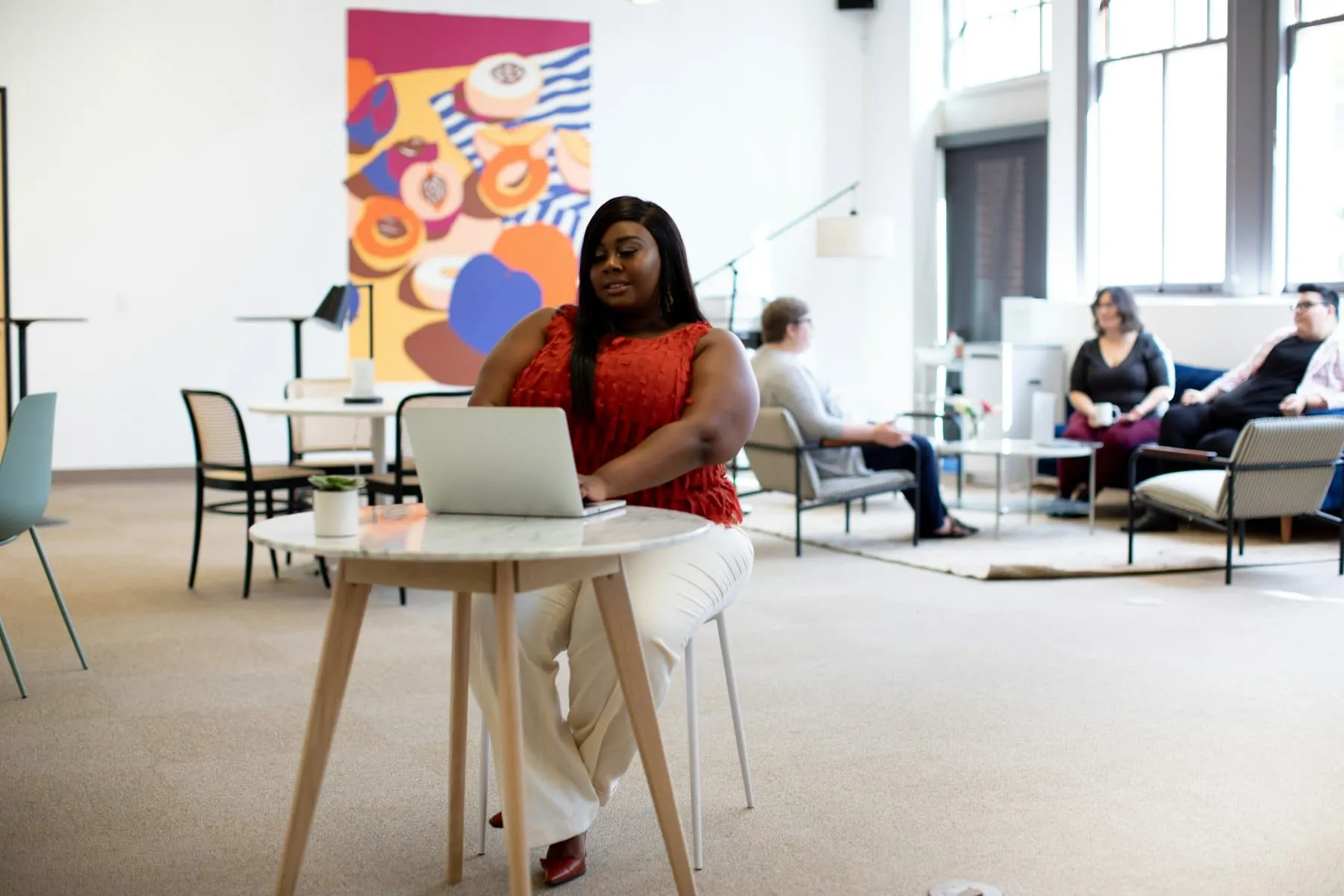 A woman working on a laptop at a desk in a bright office