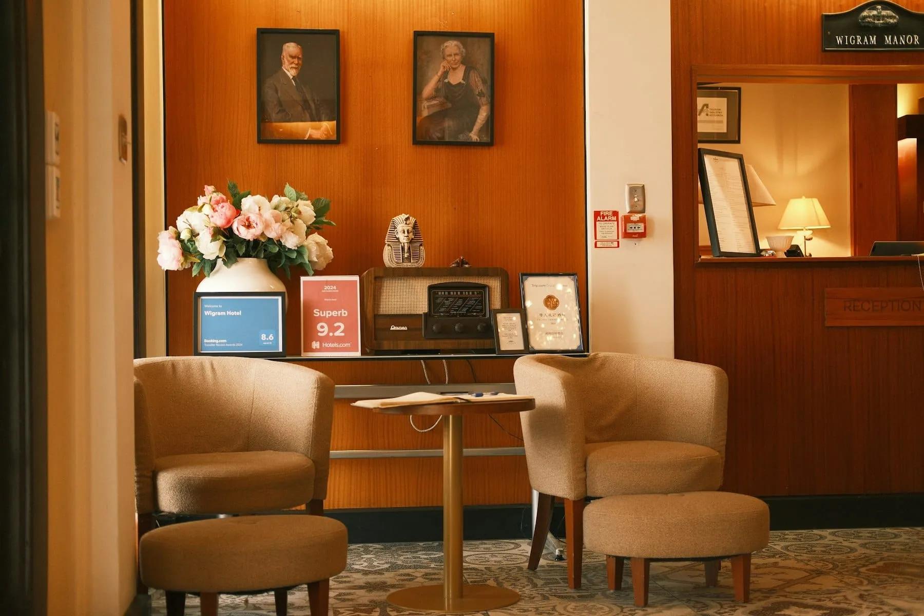 A hotel reception desk with armchairs and fresh flowers