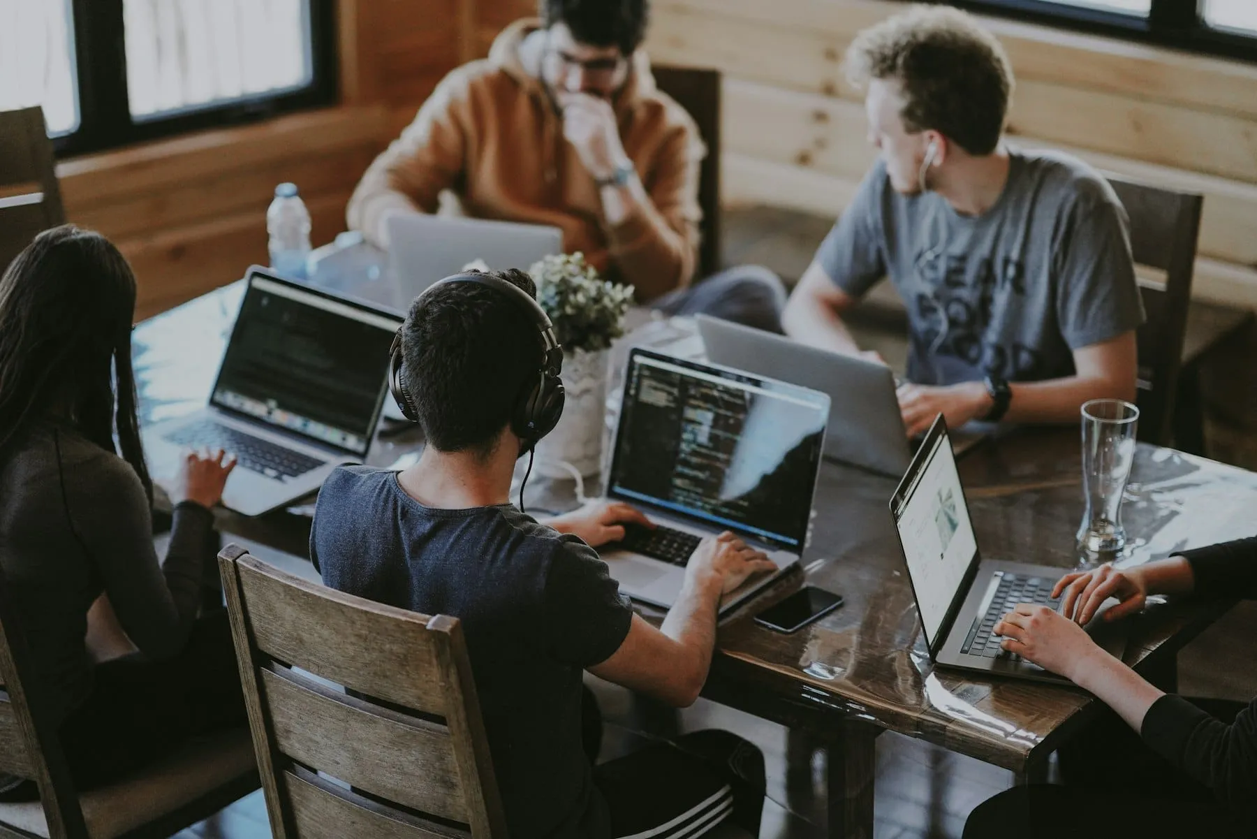 A small team working on laptops at a shared wooden table