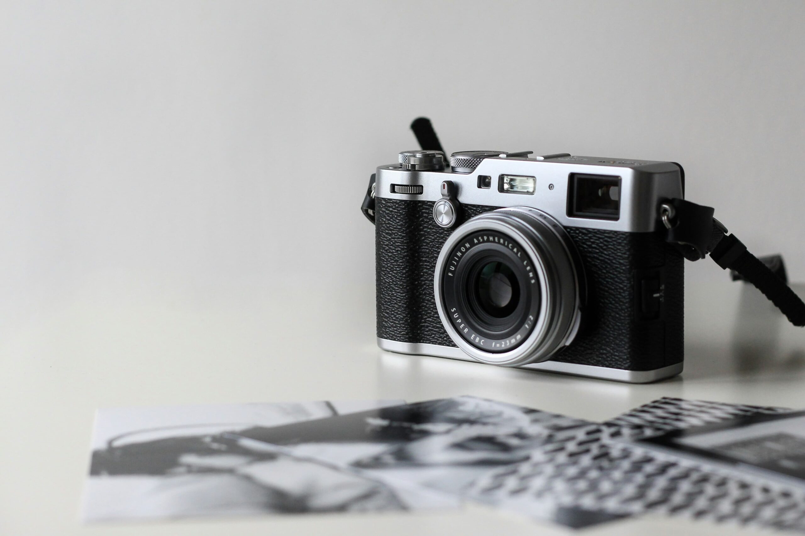 Een camera op een witte tafel naast een stapel afgedrukte foto’s
