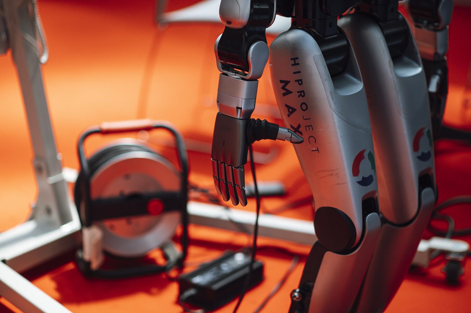 Robotic hand reaching for a tool at a technology exhibition, illustrating AI agents that act on their own