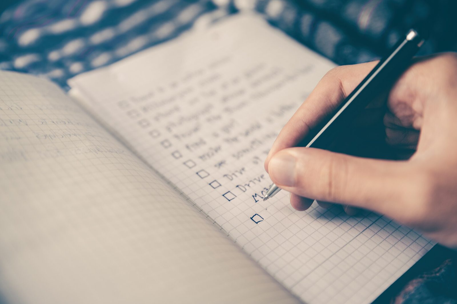 Hand ticking items on a handwritten checklist in a notebook, representing an AI-readiness checklist for hotels